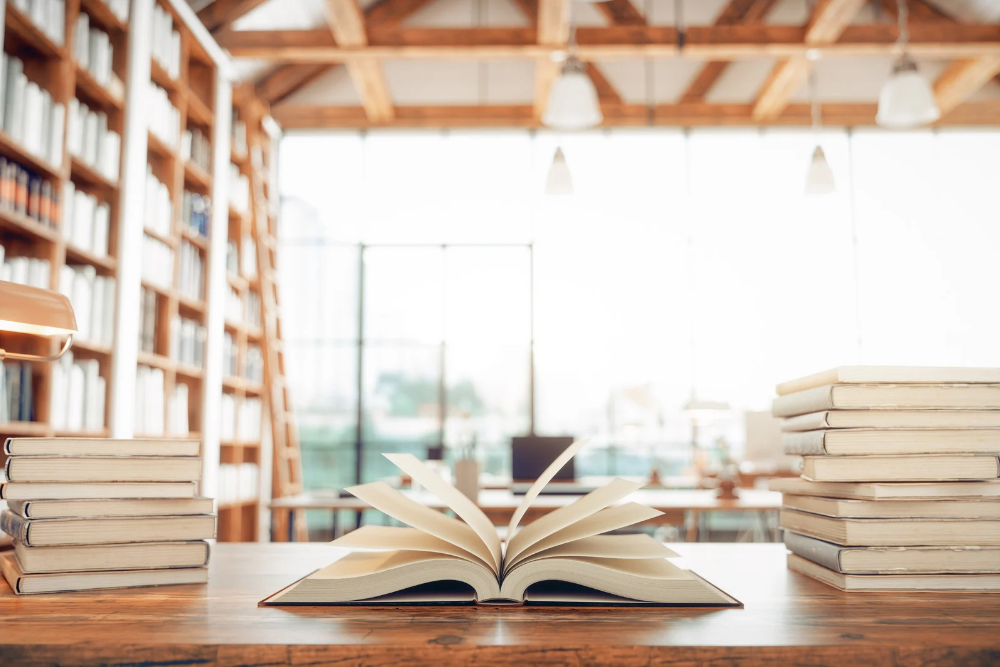 An open book on a desk in a well lit library.